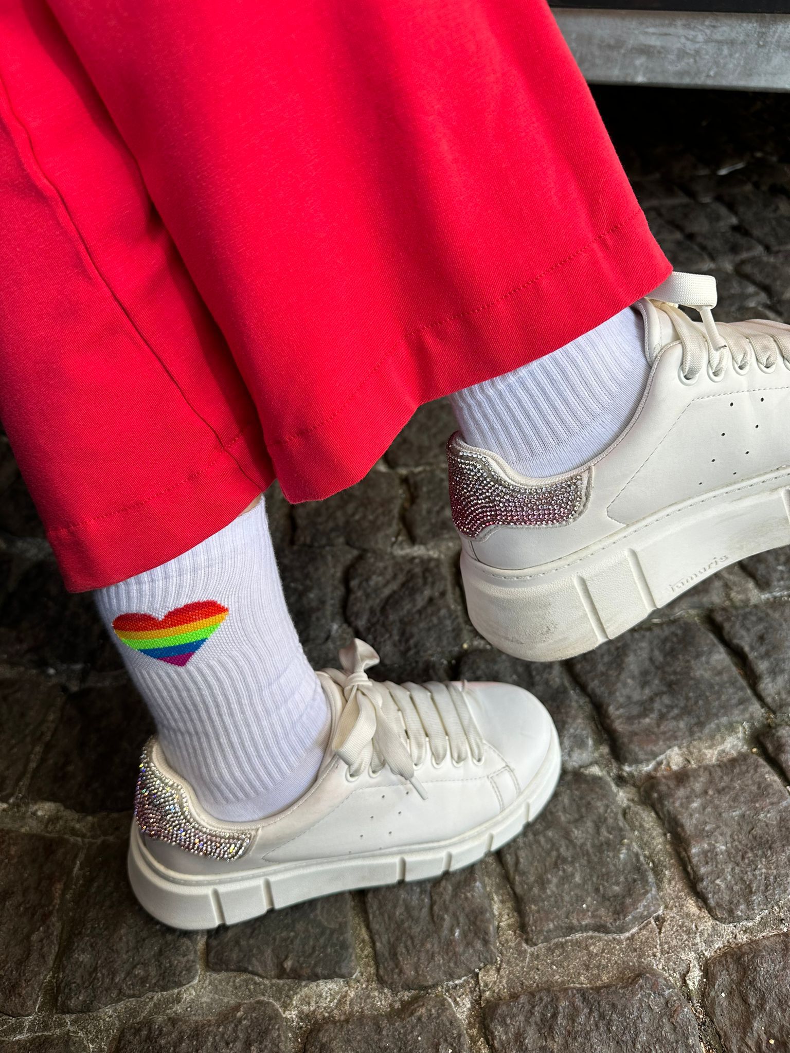 Eine Frau hat eine rote Hose und weiße Schuhe an. Auf den weißen Socken steht Liebe Digga, Liebe und ein Regenbogenherz